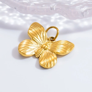 Détail d'un pendentif papillon doré avec des textures d'ailes et anneau en métal