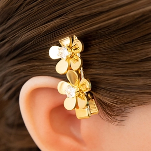 Detail of golden flower hair clip with zirconia, shown on model's dark brown hair
