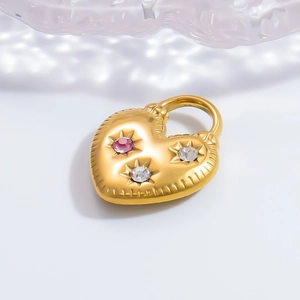 Détail macro d'un pendentif coeur doré avec strass colorés et textures de couture