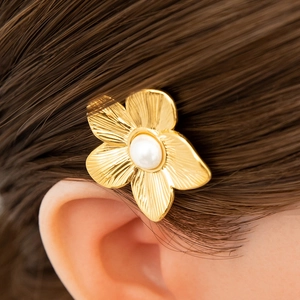 Detail einer goldenen Blumenhaarklammer mit strukturierten Blüten und weißer Perle