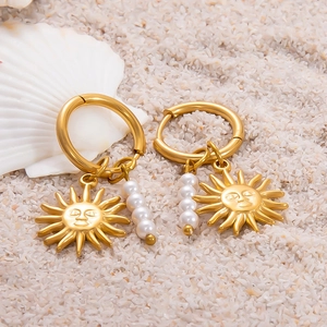 Vue détaillée des boucles d'oreilles or 18k avec breloques soleil et perles blanches