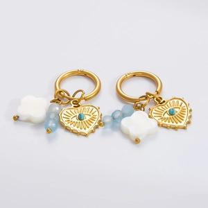 Détail de boucles d'oreilles en or 18 carats avec cœur œil protecteur et coquillage