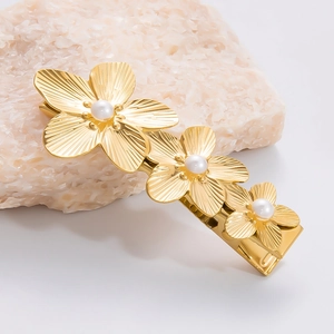 Nahaufnahme der goldenen Blumen-Haarspange mit weißen Perlen und radialer Textur