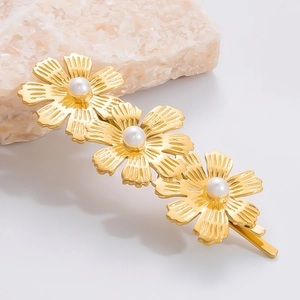 Details von drei goldenen Blumen-Haarspangen mit Perlen auf strukturiertem Stein-Hintergrund