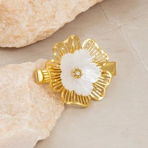 Detailed view of a gold floral hair clip with white shell petals and a sparkling zircon