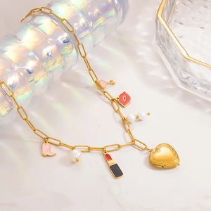 Détail d'un collier en acier doré avec médaillon cœur, perles et breloques sur verre