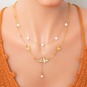 Close-up of double-layer necklace with white pearls and gold butterfly pendants