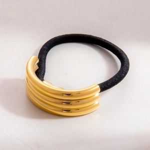 Detail eines hochelastischen schwarzen Haargummis mit dreilagigem Gold-Metallakzent