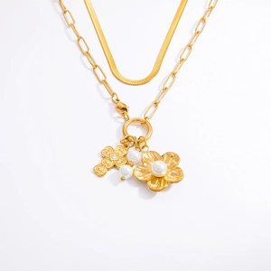 Détail du collier double doré avec chaîne serpent, fleur en perle et pendentifs croix