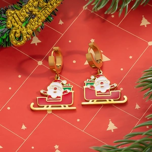 Detalle de pendientes navideños dorados con Papá Noel en trineo y decorado festivo