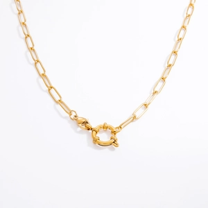 Gros plan sur un collier trombone doré avec un grand fermoir à ressort circulaire sur fond blanc