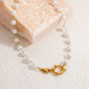 Dettaglio della collana di perle con chiusura dorata su una pietra di cristallo rosa