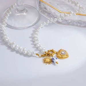 Dettaglio collana di perle con rilievo solare, perla floreale e pendente a cuore zircone