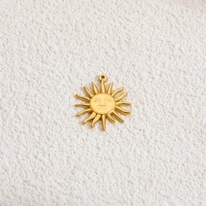 Dettaglio macro del ciondolo sole in oro 18k con rilievo del viso e raggi lucidi