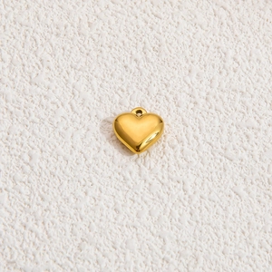 Ciondolo a cuore in oro 18k lucidato con superficie liscia su sfondo bianco ruvido