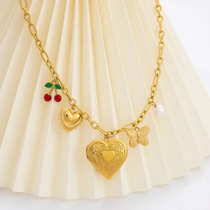 Detailansicht einer goldenen Charm-Halskette mit Kirsche, Herz-Medaillon, Schmetterling und Perle