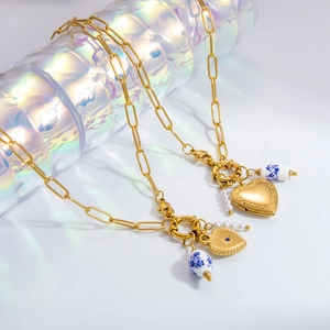 Detailed view of gold heart pendants with blue porcelain beads and chunky chain necklace