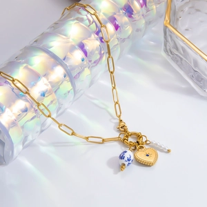 Detail of gold paperclip necklace with blue heart pendant and porcelain bead
