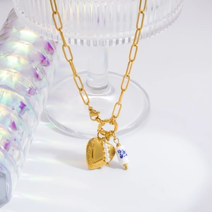 Detail of vintage gold heart pendant necklace with pearls and blue floral porcelain tube