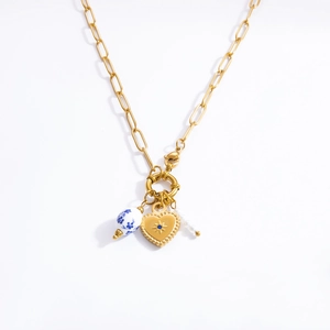 Detail of golden paperclip chain necklace with heart pendant and blue floral bead