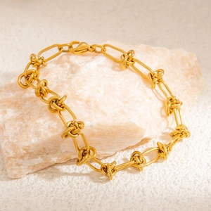 Detail of 18k gold plated stainless steel chain bracelet on a textured mineral stone base