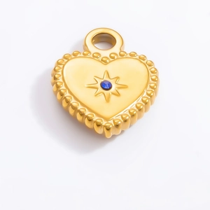 Macro shot of gold heart pendant featuring a blue gem and starburst engraving details