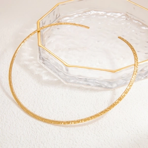 Detailed close-up of a gold hammered stainless steel choker on a glass tray