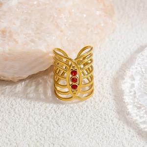 Detail of vintage golden multi-layer hollow ring with three inlaid red stones