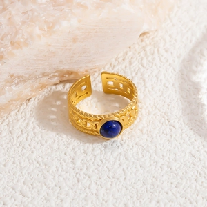 Macro detail of vintage gold stainless steel ring with woven texture and blue stone
