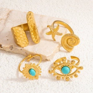 Detail of four gold rings featuring starfish, evil eye motifs and turquoise accents