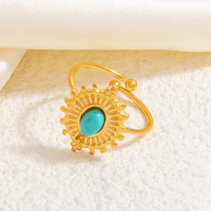 Macro shot of gold sunburst ring with turquoise stone inlay on white silk background