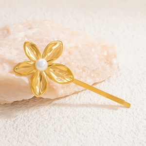 Macro shot of gold-plated flower hair clip with pearl center and textured metal petals