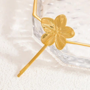 Detail of 18K gold plated floral hair clip with textured petals and polished finish