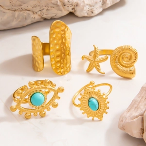 Macro view of ocean themed 18k gold rings featuring starfish, evil eye and sun elements