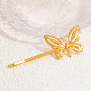Detail shot of a hollow 18K gold plated butterfly hair clip on an artistic textured surface