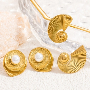Detail view of 18k gold wave shell earrings featuring white pearls on natural stone base