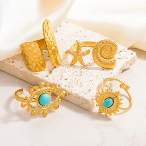 Detail of four gold 18k rings with seashell, starfish and turquoise devil eye motifs