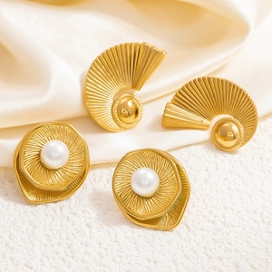 Detailed view of 18k gold wave earrings with white pearls on elegant silk fabric