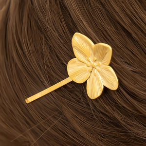 Detail of 18K gold flower hair clip with radial texture on brown hair side view