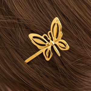Macro view of gold-plated hollow butterfly hair clip with intricate metal textures