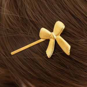 Detailed view of an 18K gold bow-shaped hair clip with elegant textured ribbed metal finish