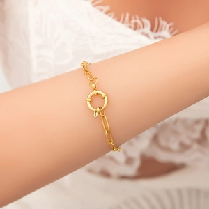 Detail van een 18K goudkleurige stalen armband met grote ronde veerringsluiting om de pols
