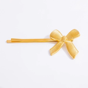 Detailed view of golden 18K gold-plated bow hair clip with textured wavy finish