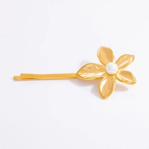 Close-up of gold flower hair clip with white pearl center and textured metal petals