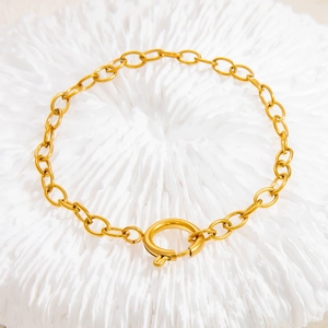 Detail van een gouden roestvrijstalen schakelarmband met een grote ronde veerringslot