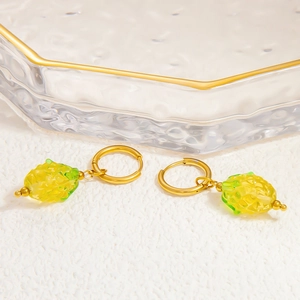 Gros plan de boucles d'oreilles dorées avec pendentifs ananas en résine sur plateau