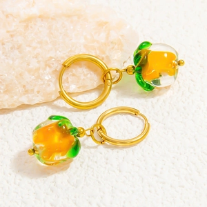 Détail de boucles d'oreilles dorées 18K avec pendentifs fruits en verre sur pierre