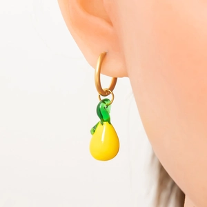 Détail du pendentif poire en verre sur créole dorée présenté sur un modèle d'oreille
