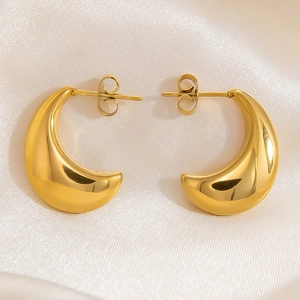 Macro shot of chunky gold-plated 18K stainless steel hoop earrings on white silk