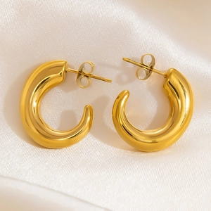 Detailed close-up of 18K gold-plated chunky C-shape hoop earrings on white silk fabric
